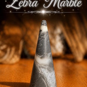 K&ouml;nnte beinhalten: Ein kegelf&ouml;rmiger Ringst&auml;nder aus Zebra-Marmor mit einer glatten, polierten Oberfl&auml;che und wirbelnden Mustern in Dunkelgrau, Schwarz und Wei&szlig;. Der Text "Zebra Marble" ist in wei&szlig;er Schreibschrift &uuml;ber dem Objekt abgebildet.