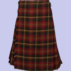 Op de afbeelding: Een traditionele kilt in een rood, zwart en goud geruit patroon. De kilt heeft een gefranjerde rand en een gespsluiting. Dit kledingstuk is een klassiek stuk Schotse kleding.