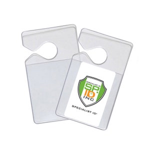 May include: Two clear plastic ID badge holders with a hook for hanging on a rearview mirror. The holder on the right has a white label with a green and orange logo that says "Specialist ID SP. INC. SPECIALIST ID".