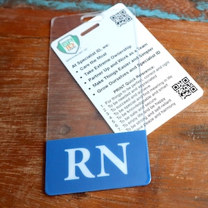 Puede incluir: Una placa de pl&aacute;stico azul con las letras "RN" en blanco. La placa tiene una funda de pl&aacute;stico transparente y un mensaje impreso sobre la identificaci&oacute;n del especialista, el cuidado, la propiedad, el trabajo en equipo y el crecimiento.