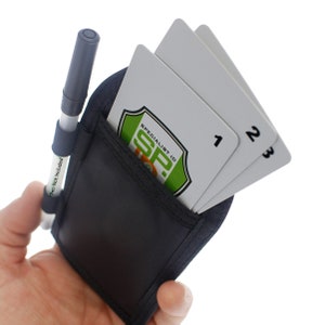 May include: A black pouch with a zippered pocket and a pen holder. The pouch has two white cards inside with the numbers 1, 2, and 3 printed on them. The pouch also has a green and orange logo that says "Specialist ID SP."