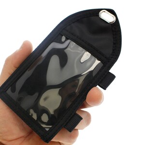 May include: Black nylon badge holder with a clear plastic window and a strap for attaching to a belt or wrist.