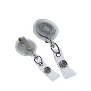 May include: Two clear retractable badge holders with a silver clip and a clear strap. The holders are designed to hold ID cards or other small items.