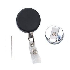 May include: A black retractable badge reel with a silver clip and a white strap. The reel has a black plastic casing and a silver metal clip. The strap is white and has a small silver button.