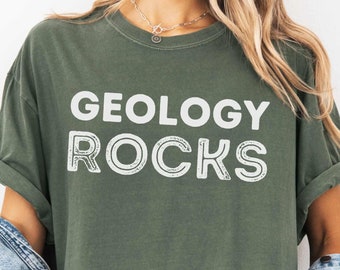 May include: A green t-shirt with the text "Geology Rocks" in white lettering. The shirt has a distressed look and is made of a soft, comfortable fabric.