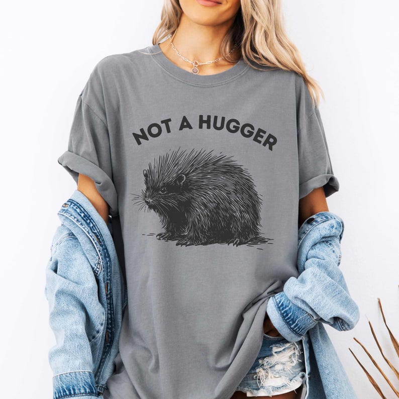 May include: A grey t-shirt with the text "Not a hugger" and a black and white illustration of a porcupine.