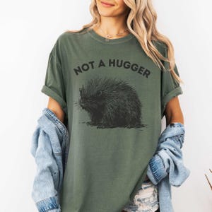 May include: A green t-shirt with a black and white illustration of a porcupine and the text "Not a Hugger".