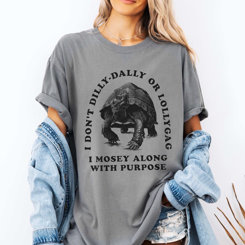 May include: Gray t-shirt with a black graphic of a turtle and the text "I don't dilly-dally or lollygag I mosey along with purpose".