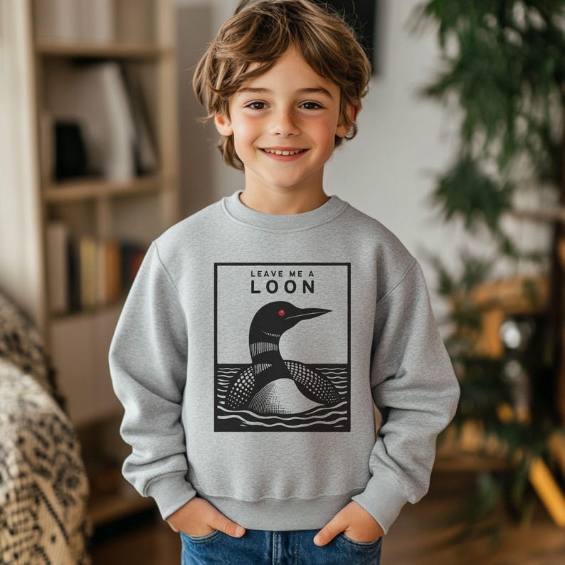 May include: A gray sweatshirt with a black and white illustration of a loon on the front. The text "Leave me a loon" is printed above the loon.
