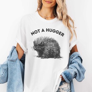 May include: White t-shirt with a black and white illustration of a porcupine and the text "Not a hugger".