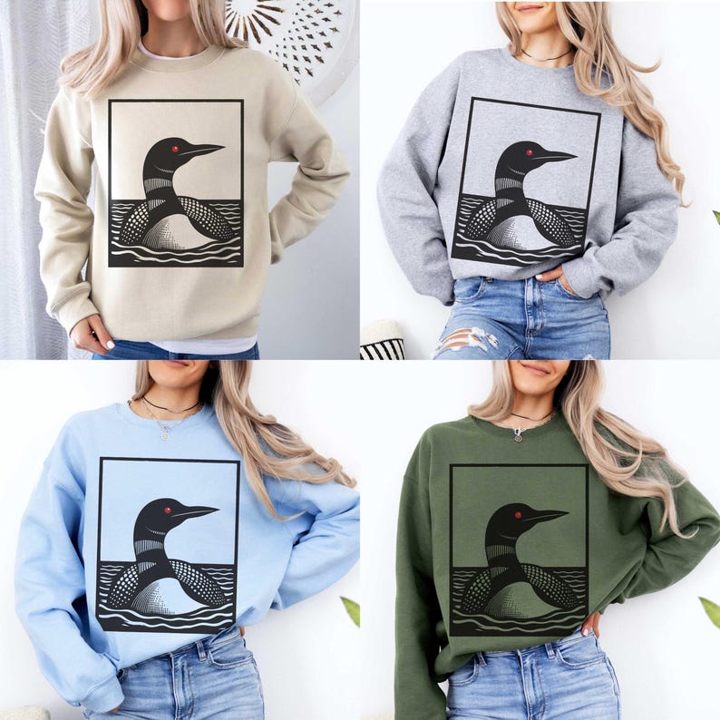 May include: Four different color sweatshirts with a black and white graphic of a loon on the front. The loon is in a square frame with a wavy line at the bottom to represent water. The sweatshirts are beige, gray, light blue, and dark green.