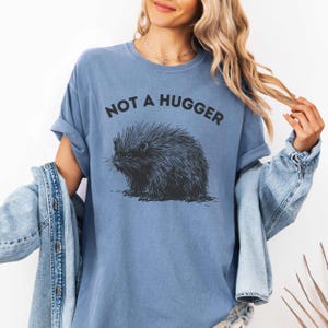 May include: A blue t-shirt with a black and white illustration of a porcupine and the text "Not a hugger".