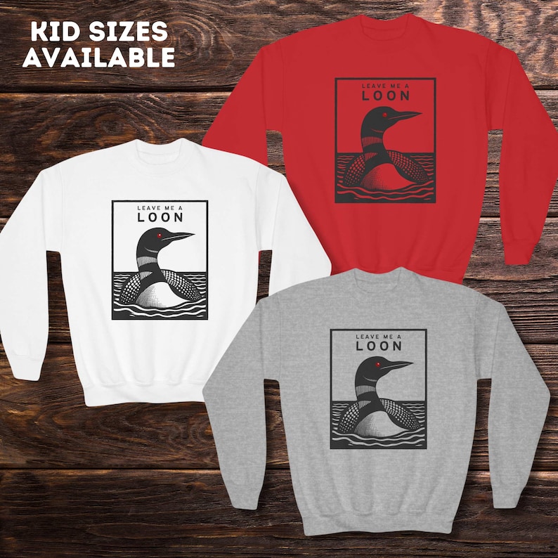 May include: Three sweatshirts in red, white, and gray with a black and white illustration of a loon on each. The loon has red eyes and the text "Leave me a loon" is printed above the loon.