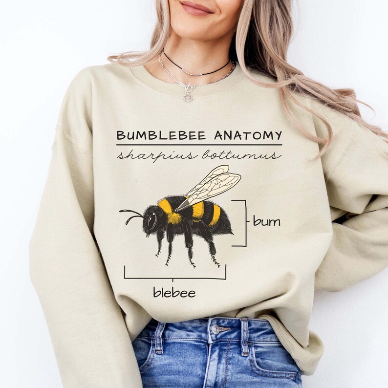Pu&ograve; includere: Una felpa beige chiaro con una grafica di un bombo e il testo "Bumblebee Anatomy, sharpus bottomus, bum, blebee".