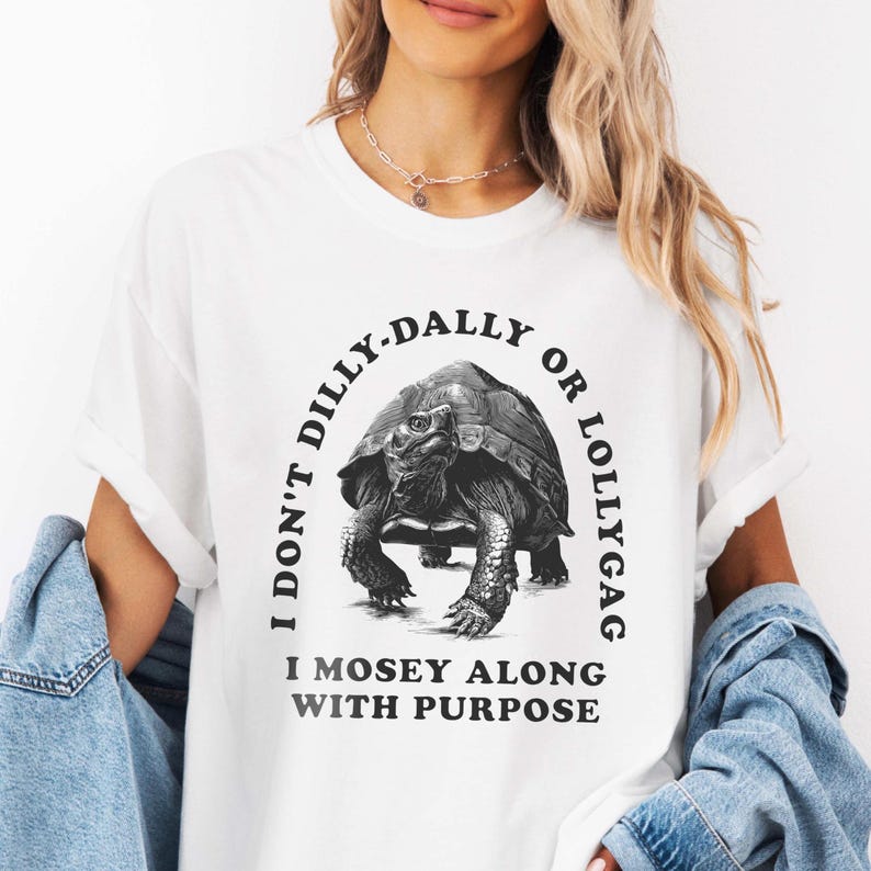 May include: White t-shirt with a black and white illustration of a turtle and the text "I don't dilly-dally or lollygag I mosey along with purpose."