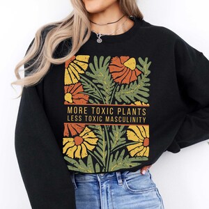 May include: Black sweatshirt with a floral print and the text "More Toxic Plants Less Toxic Masculinity".