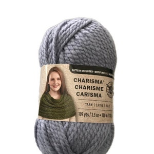 Może przedstawiać: Motka szarej przędzy o nazwie Charisma, Charisme, Carisma. Przędza ma 109 jardów i 3,5 uncji. Etykieta zawiera wzór na szalik.