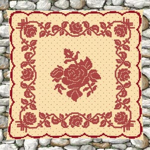 May include: A cream-colored, square tablecloth with a red floral cross-stitch design. The border and central rose motif are red, with smaller floral patterns along the edges. The background has a dotted pattern.