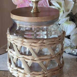 Tarro decorativo de cristal transparente con envoltura de mimbre.