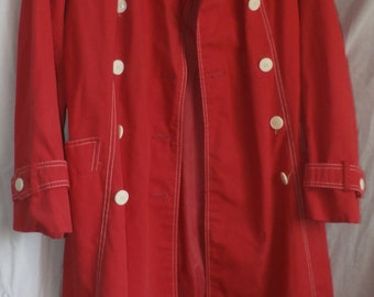 May include: A red trench coat with white stitching and white buttons. The coat has a double breasted closure and a belt.