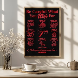 Puede incluir: Un póster negro enmarcado con texto e ilustraciones en rojo. El texto dice "Be Careful What You Wish For" y enumera varios deseos. Una taza de café blanca y una bandeja de madera están en primer plano.