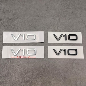 Puede incluir: Cuatro pegatinas de emblema de coche V10, dos en plata y dos en negro. Los emblemas plateados miden 80 mm de ancho. Las pegatinas est&aacute;n sobre papel blanco, listas para su aplicaci&oacute;n.