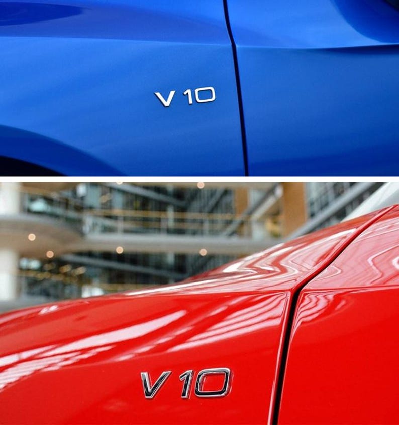 Puede incluir: Primer plano de dos paneles de coche, uno azul y otro rojo. Cada panel tiene un emblema plateado "V 10". El panel azul est&aacute; arriba, el rojo abajo. La imagen destaca el acabado brillante de la pintura del coche.