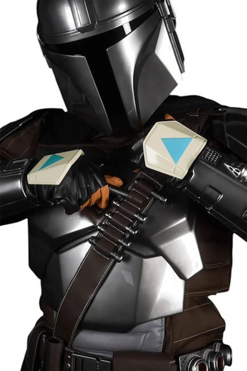 May include: A costume featuring a metallic silver helmet with a black visor, a chest plate, and dark brown fabric elements. The outfit includes a brown bandolier with silver cylindrical cartridges and black gloves with white and blue accents.