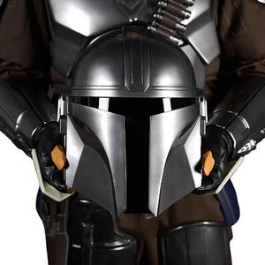 May include: A metallic silver helmet with a T-shaped visor held in front of a matching suit of armor. The armor features dark brown fabric, shoulder pauldrons, and a bandolier with silver cartridges across the chest, all in a polished finish.