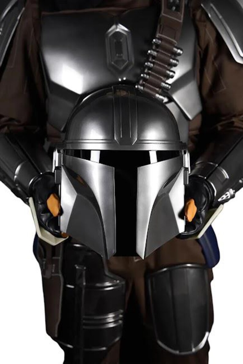 May include: A metallic silver helmet with a T-shaped visor held in front of a matching suit of armor. The armor features dark brown fabric, shoulder pauldrons, and a bandolier with silver cartridges across the chest, all in a polished finish.