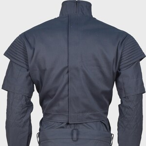 Peut inclure: Une veste gris fonc&eacute; dot&eacute;e d'un col montant, d'une fermeture centrale verticale et de panneaux d'&eacute;paules pliss&eacute;s. Les manches pr&eacute;sentent un motif en losanges matelass&eacute; sur la partie inf&eacute;rieure, avec une conception structur&eacute;e et uniforme.