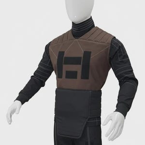 May include: A brown and black tactical vest worn over a black long-sleeve shirt with white geometric line detailing. The vest features a quilted upper chest panel, a central black rectangular emblem, and a solid black lower abdominal guard panel.