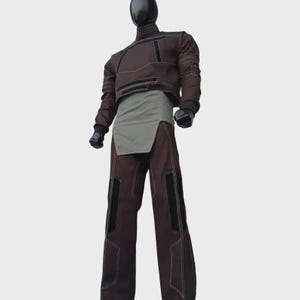Puede incluir: Una parte superior de manga larga marr&oacute;n oscuro con cuello alto y detalles negros, combinada con pantalones marr&oacute;n oscuro a juego con paneles negros y costuras blancas en contraste. Un panel de tela verde oliva claro cubre la cintura.