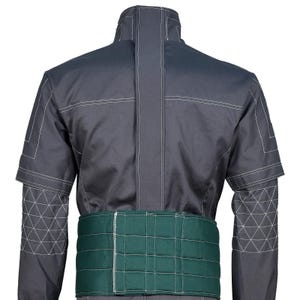 May include: A dark gray jacket featuring a high collar, a vertical center seam, and white topstitching. The sleeves have a geometric triangular pattern on the forearms. A wide, quilted dark green belt is attached around the waist area.