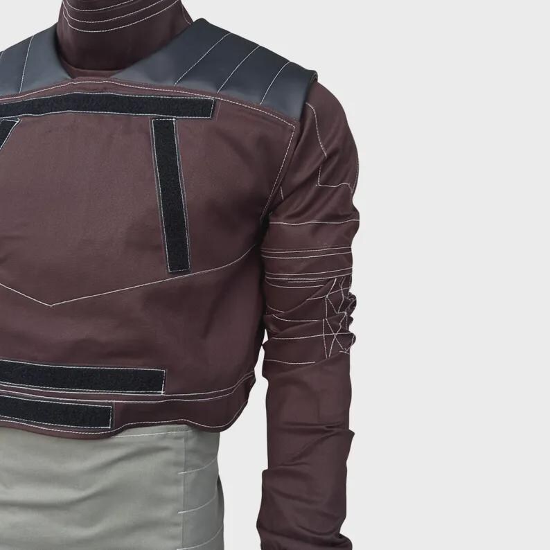 Puede incluir: Una camisa de manga larga color granate oscuro con cuello alto, paneles negros en los hombros y tiras de velcro negras en el pecho y la cintura. La prenda incluye costuras blancas en contraste a lo largo de todas las mangas.