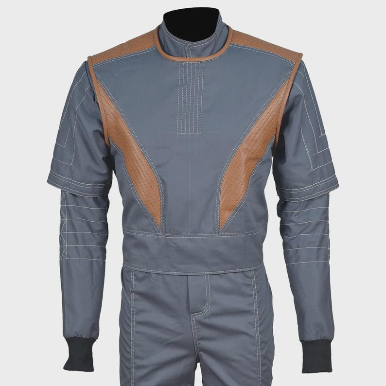 May include: A grey jumpsuit featuring brown leather-like panels on the chest and shoulders. The garment includes a high collar, short sleeves layered over long sleeves with white contrast stitching, and black ribbed cuffs at the wrists.