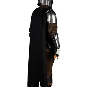 May include: A full-body costume featuring a metallic silver helmet and shoulder armor, a long black cape, and a brown textured jumpsuit. The outfit includes silver forearm gauntlets, dark brown boots, and brown gloves with a small light blue accent.