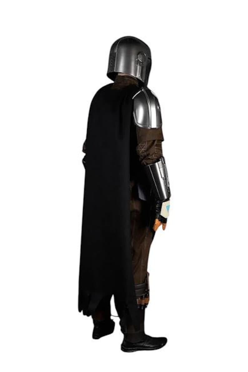 May include: A full-body costume featuring a metallic silver helmet and shoulder armor, a long black cape, and a brown textured jumpsuit. The outfit includes silver forearm gauntlets, dark brown boots, and brown gloves with a small light blue accent.