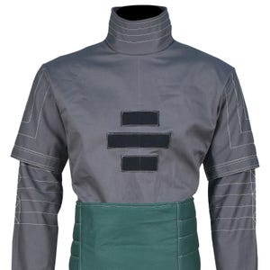 May include: A grey mock neck shirt featuring white geometric line stitching on the shoulders and sleeves, three horizontal black rectangular patches on the chest, and a wide, dark green horizontal panel around the waist with quilted stitching.