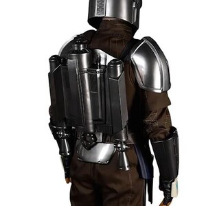 May include: A full-body costume featuring a metallic silver helmet, matching shoulder pauldrons, and a dark gray jetpack worn over a brown long-sleeved jacket and trousers. The ensemble includes black gauntlets and dark utility gear components.