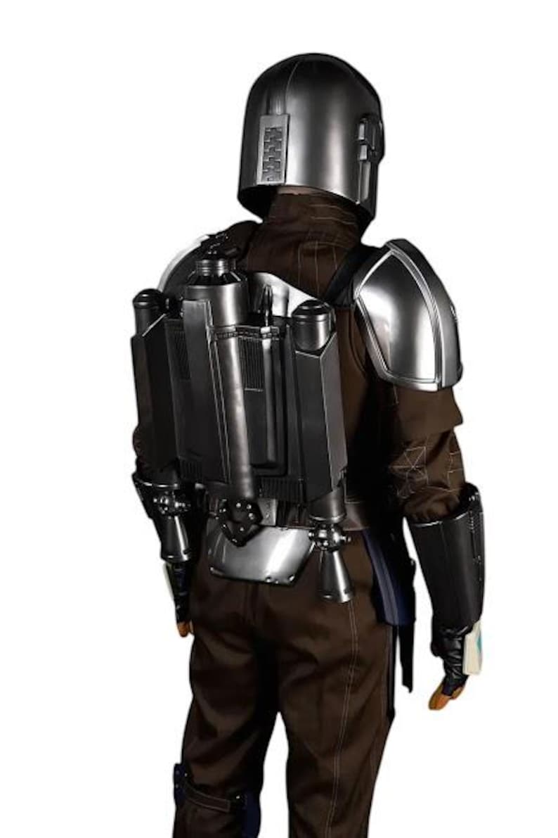 May include: A full-body costume featuring a metallic silver helmet, matching shoulder pauldrons, and a dark gray jetpack worn over a brown long-sleeved jacket and trousers. The ensemble includes black gauntlets and dark utility gear components.
