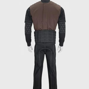 May include: A full-body costume set featuring a black long-sleeved top with white geometric stitching on the sleeves, a brown vest with quilted shoulder detailing, a black waist belt with a grid pattern, and matching black trousers with white seams.