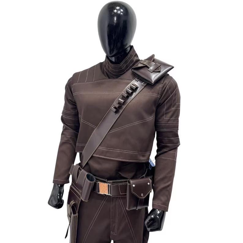 Peut inclure: Une tunique &agrave; manches longues et un pantalon assorti de couleur marron fonc&eacute; port&eacute;s par un mannequin noir. La tenue comprend une bandouli&egrave;re diagonale avec des boucles int&eacute;gr&eacute;es et une petite pochette, ainsi qu'une ceinture utilitaire.