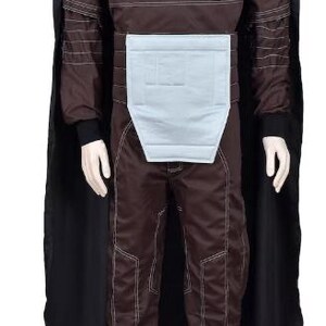 May include: A brown long-sleeved jumpsuit featuring white contrast stitching, a high collar, and a light blue rectangular abdominal panel. The garment includes a black cape draped over the shoulders and long pants with matching white stitching details.