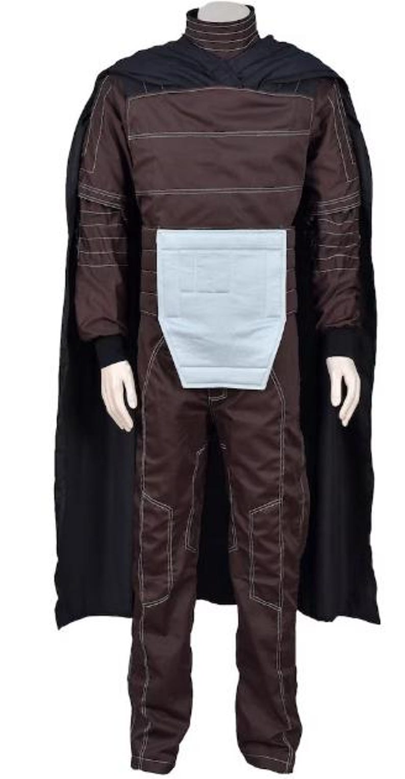 May include: A brown long-sleeved jumpsuit featuring white contrast stitching, a high collar, and a light blue rectangular abdominal panel. The garment includes a black cape draped over the shoulders and long pants with matching white stitching details.