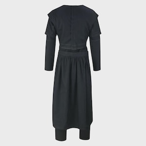 May include: A solid black long-sleeved garment featuring a cropped bodice with structured shoulders and a high neckline, paired with a matching high-waisted, pleated midi-length skirt. The ensemble is constructed with visible tonal stitching.