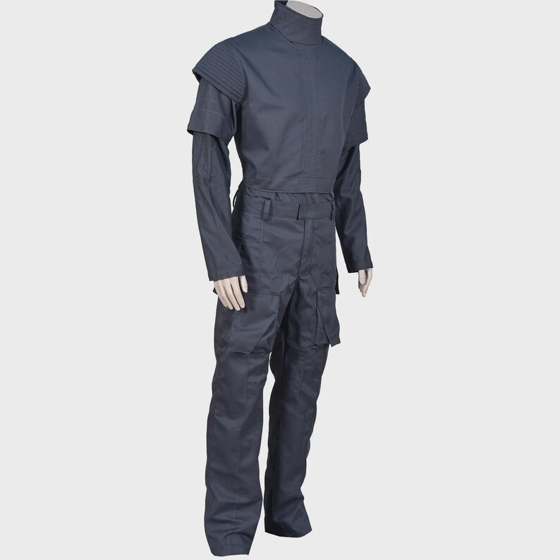Peut inclure: Un uniforme tactique gris fonc&eacute; compos&eacute; d'un haut &agrave; manches longues avec un col montant et des d&eacute;tails c&ocirc;tel&eacute;s aux &eacute;paules, associ&eacute; &agrave; un pantalon cargo assorti dot&eacute; de grandes poches lat&eacute;rales et d'une ceinture structur&eacute;e sur mannequin.