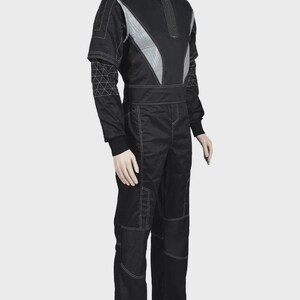 Puede incluir: Un mono negro con cuello alto, paneles de hombro gris plateado y costuras blancas en contraste. Las mangas incluyen un patr&oacute;n de rejilla geom&eacute;trica en los antebrazos, mientras que las piernas presentan secciones de rodilla reforzadas y pu&ntilde;os acanalados.