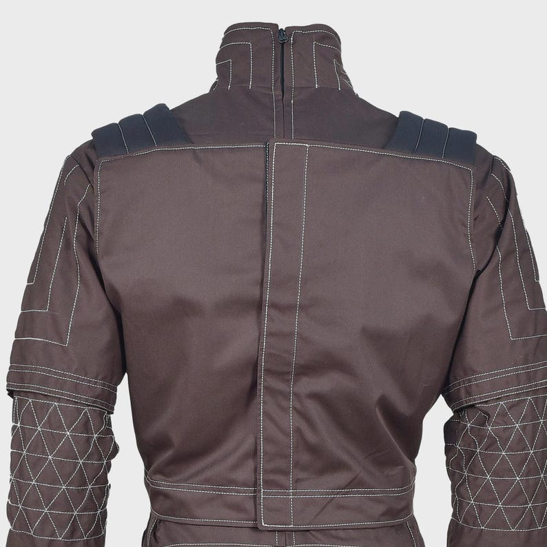 K&ouml;nnte beinhalten: Eine dunkelbraune Jacke mit Stehkragen und zentralem Rei&szlig;verschluss, wei&szlig;en Kontrastn&auml;hten und schwarzen, gepolsterten Schulterpartien. Die &Auml;rmel weisen ein gestepptes Dreiecksmuster auf, w&auml;hrend der R&uuml;cken ein vertikales Paneel besitzt.
