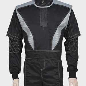 Puede incluir: Una chaqueta de estilo carreras en color negro con cuello alto, paneles acolchados plateados en los hombros y costuras blancas en contraste. Las mangas presentan un patr&oacute;n geom&eacute;trico triangular, con una cintura ancha y pu&ntilde;os acanalados negros.